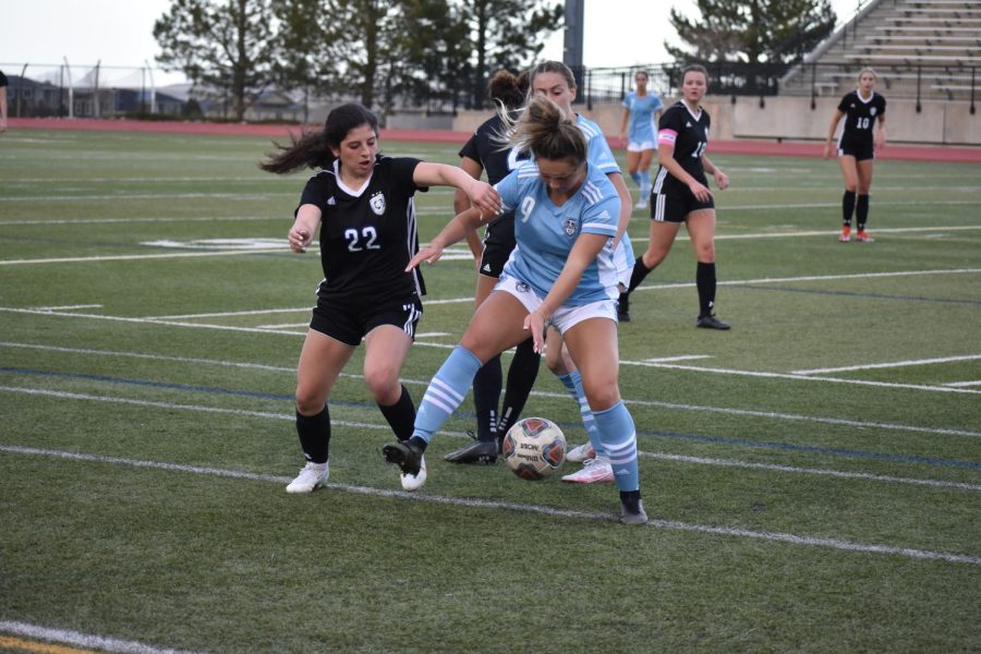 Isa Dillehay (22) attempting to win the ball around a Valor player.