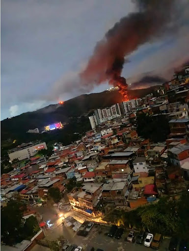 Fire at Fuerte Tiuna, Venezuela's largest military complex, is seen from a distance after a series of explosions in Caracas on January 3, 2026 (Photo by AFP via Getty Images).