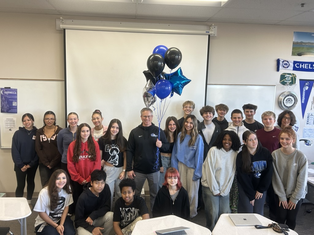 Mr. Bailey celebrates his Teacher of the Year award with students, marking a moment of recognition and community.